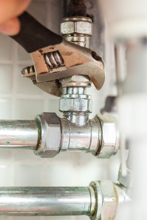 Close up of hand checking pipes with wrench